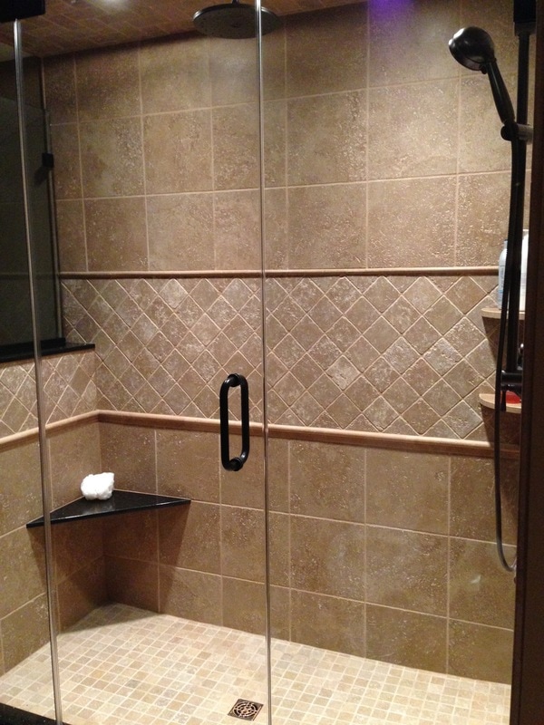 Granite seat, tile pattern, frameless shower door, handheld shower, rain head shower, stone